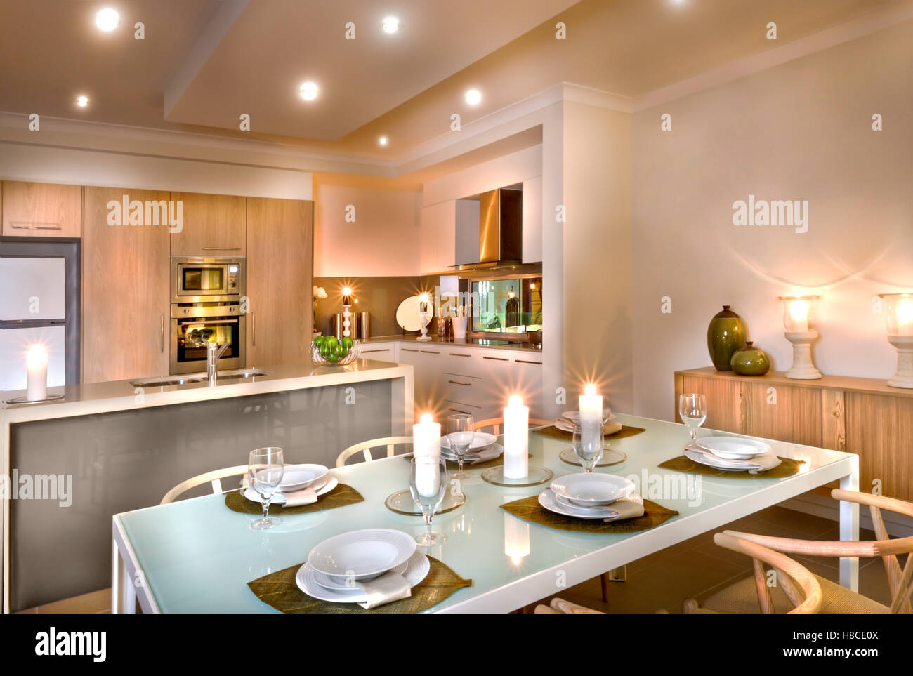 Moderna cucina e sala da pranzo con candele bianche ovunque, bicchieri di  vino e piatti sul tavolo ci sono sedie di legno Foto stock - Alamy