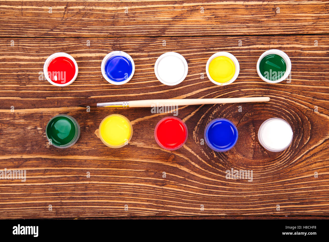 Vernici acriliche in vasi in prossimità della spazzola, sul retro dello sfondo in legno Foto Stock