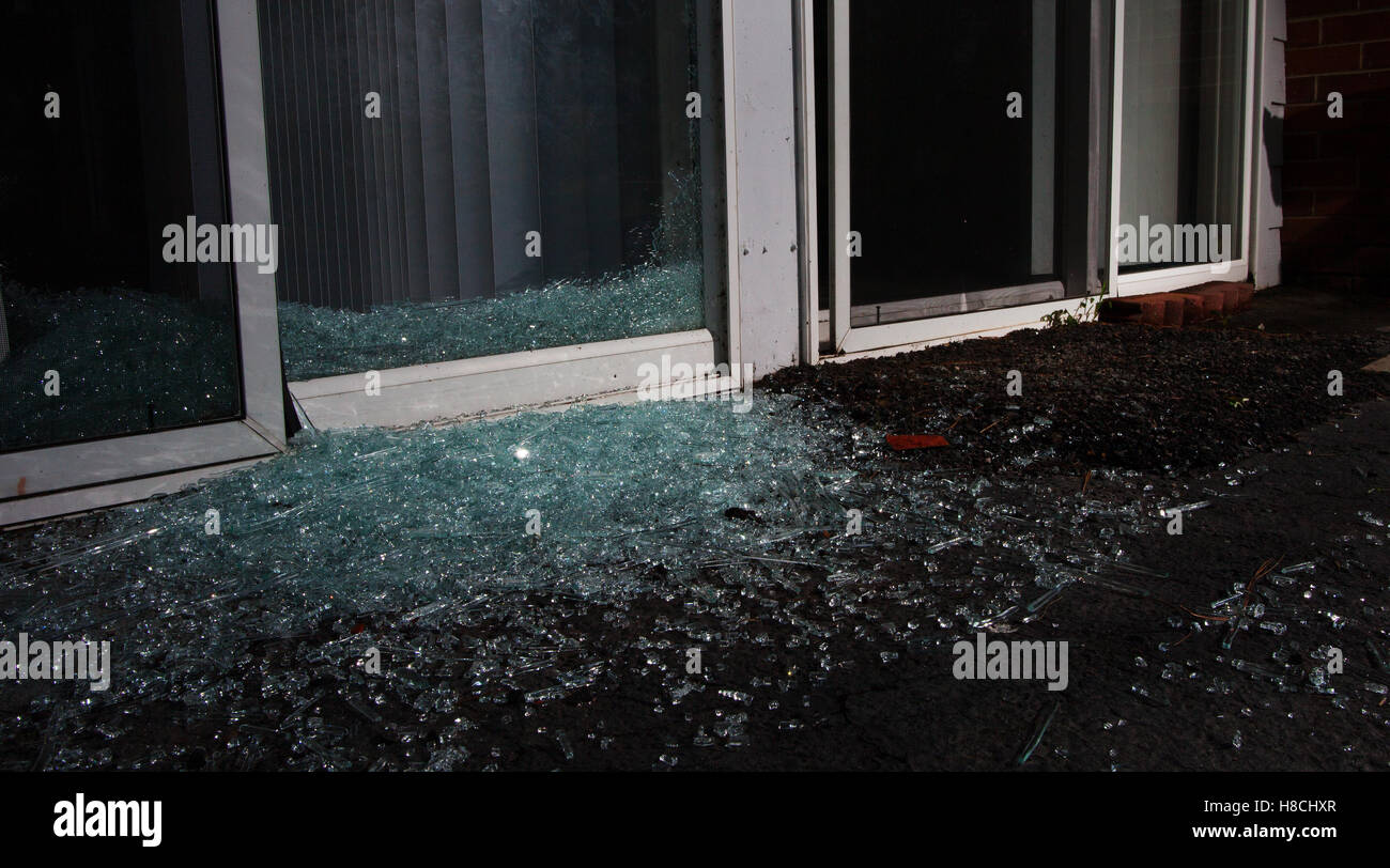 Vetri rotti e pezzi di mattoni a terra dopo un furto con scasso Foto Stock