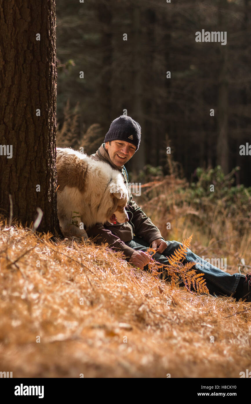 Uomo e cane godendo la vita all'aperto insieme escursionismo cercando felice avendo divertimento nei boschi tra la natura in autunno colori rientrano Foto Stock