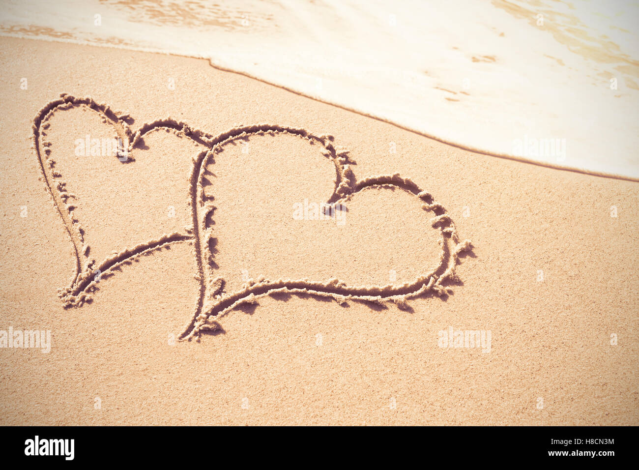 Cuore forme disegnate sulla sabbia Foto Stock