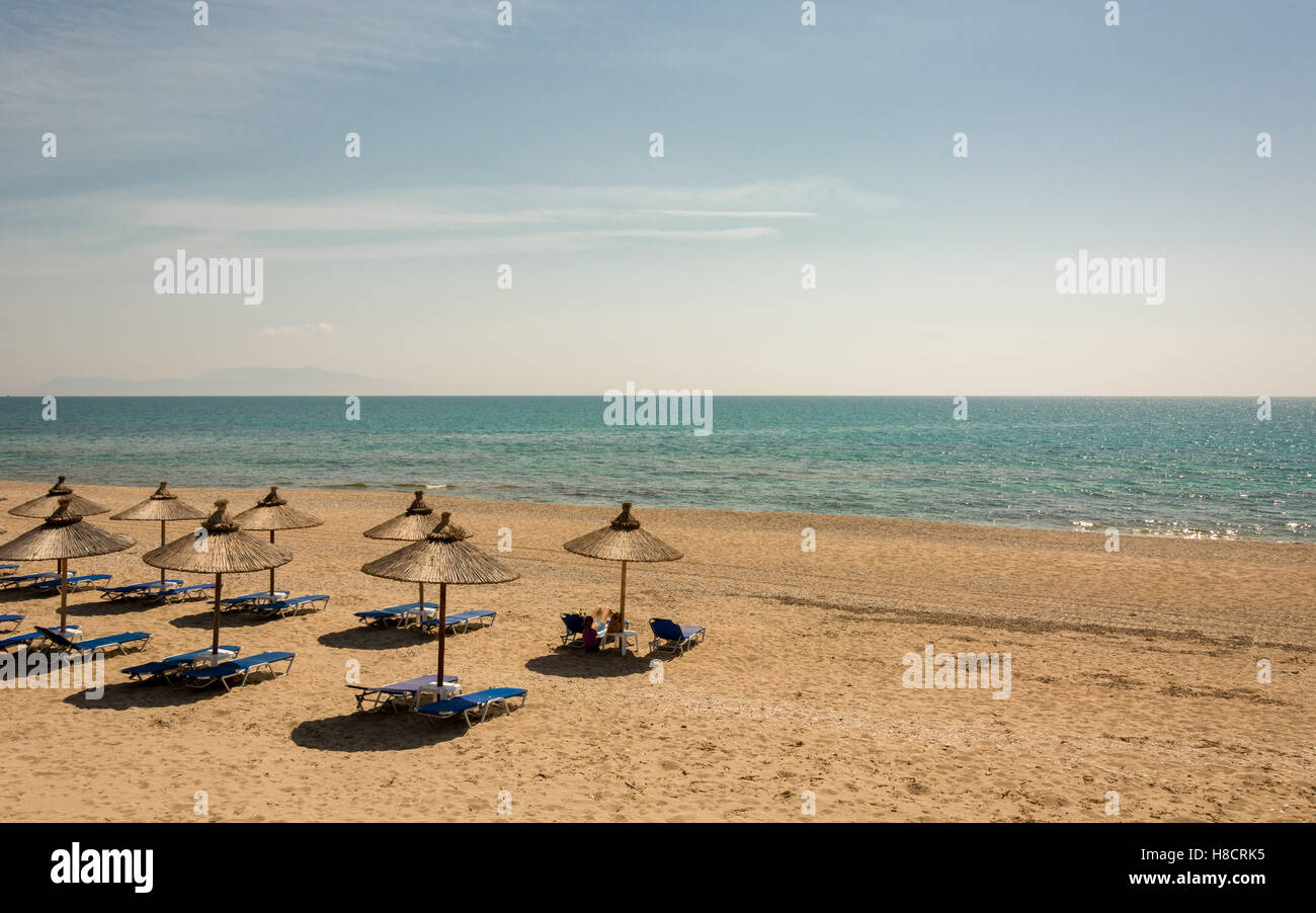 Un sistema organizzato di spiaggia e di fronte il mare blu con diversi vuoto lettini e ombrelloni Foto Stock