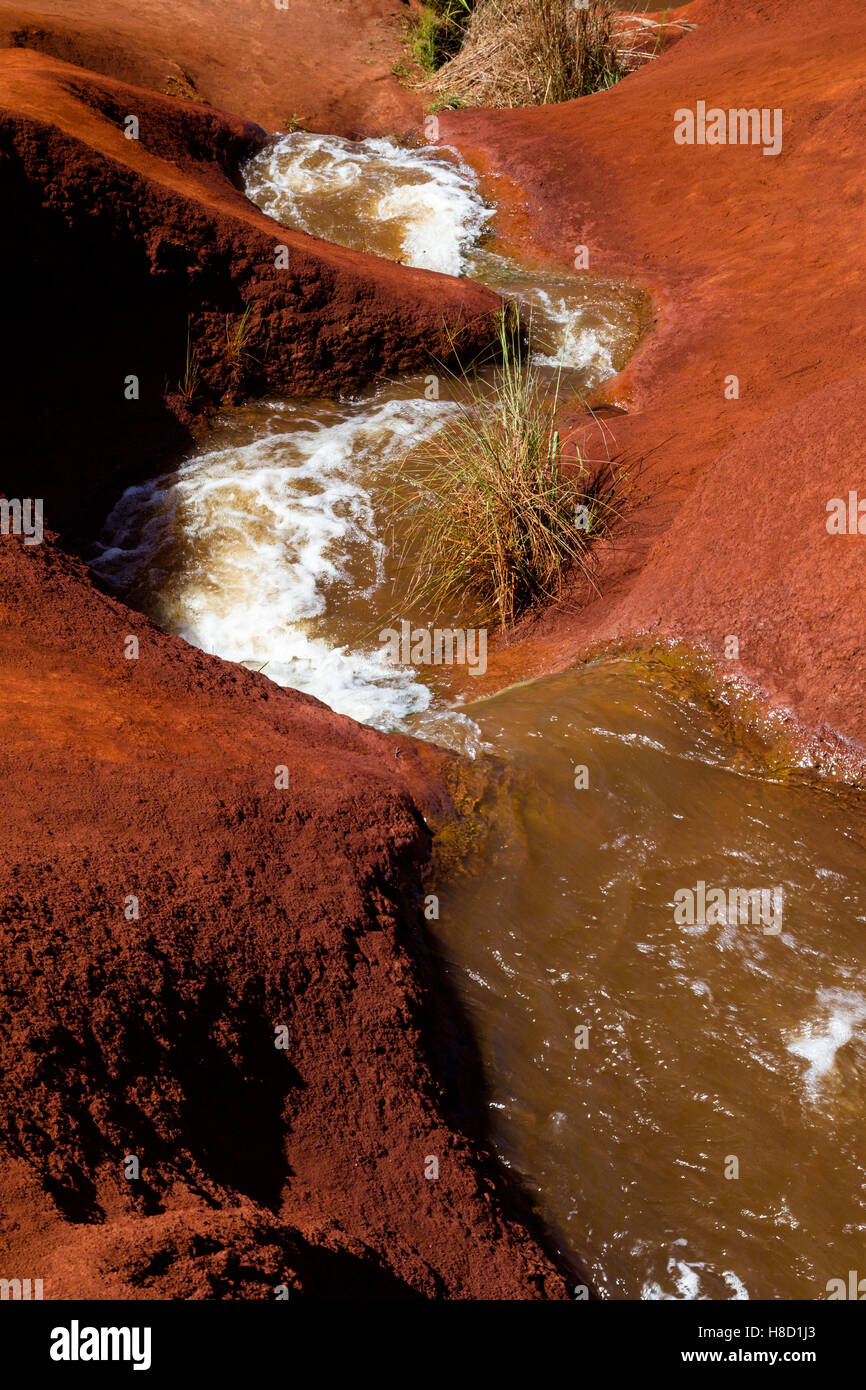 Una piccola cascata scavando in terra rossa nel Canyon di Waimea sulla Kauai, Hawaii, Stati Uniti d'America. Foto Stock