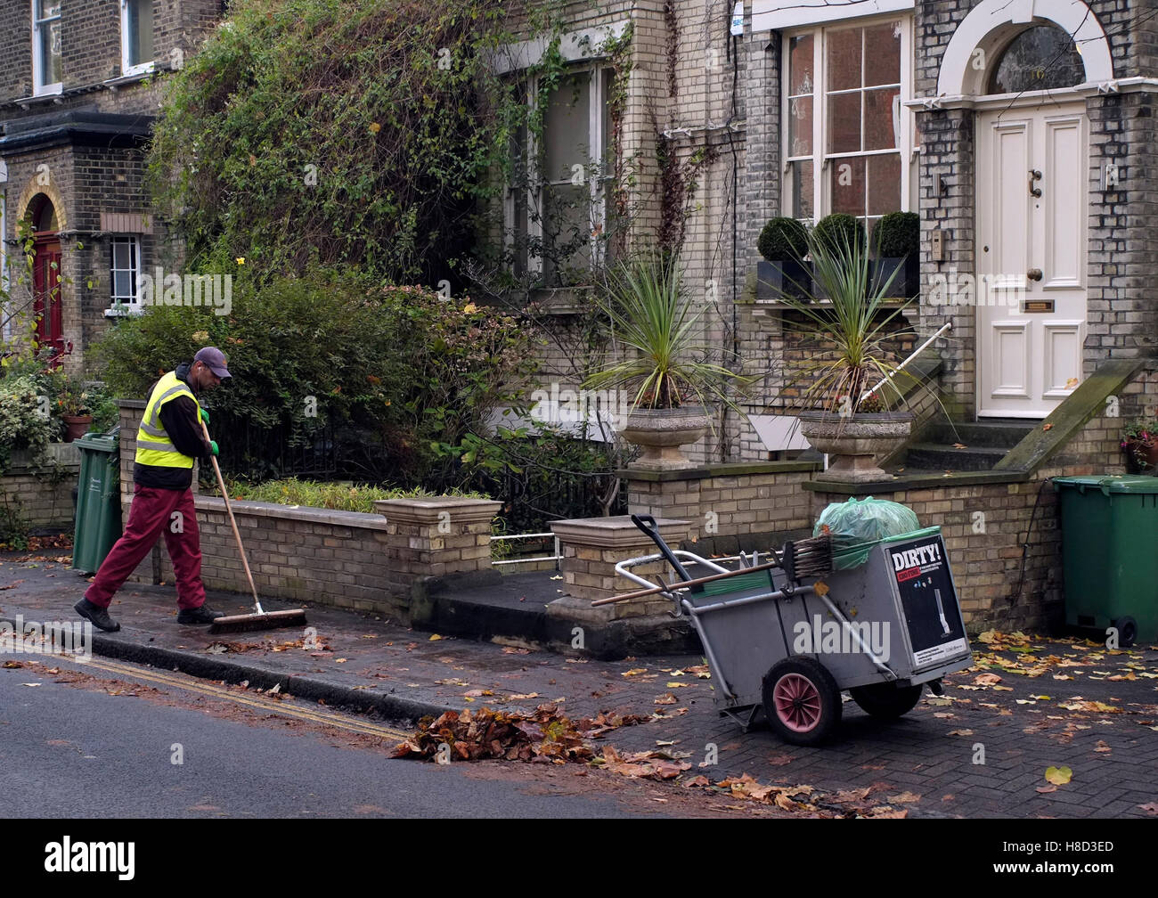 Un pulitore di via spazza le foglie in una strada residenziale di Hampstead, Londra, Gran Bretagna il 10 novembre 2016. © Giovanni Voos Foto Stock