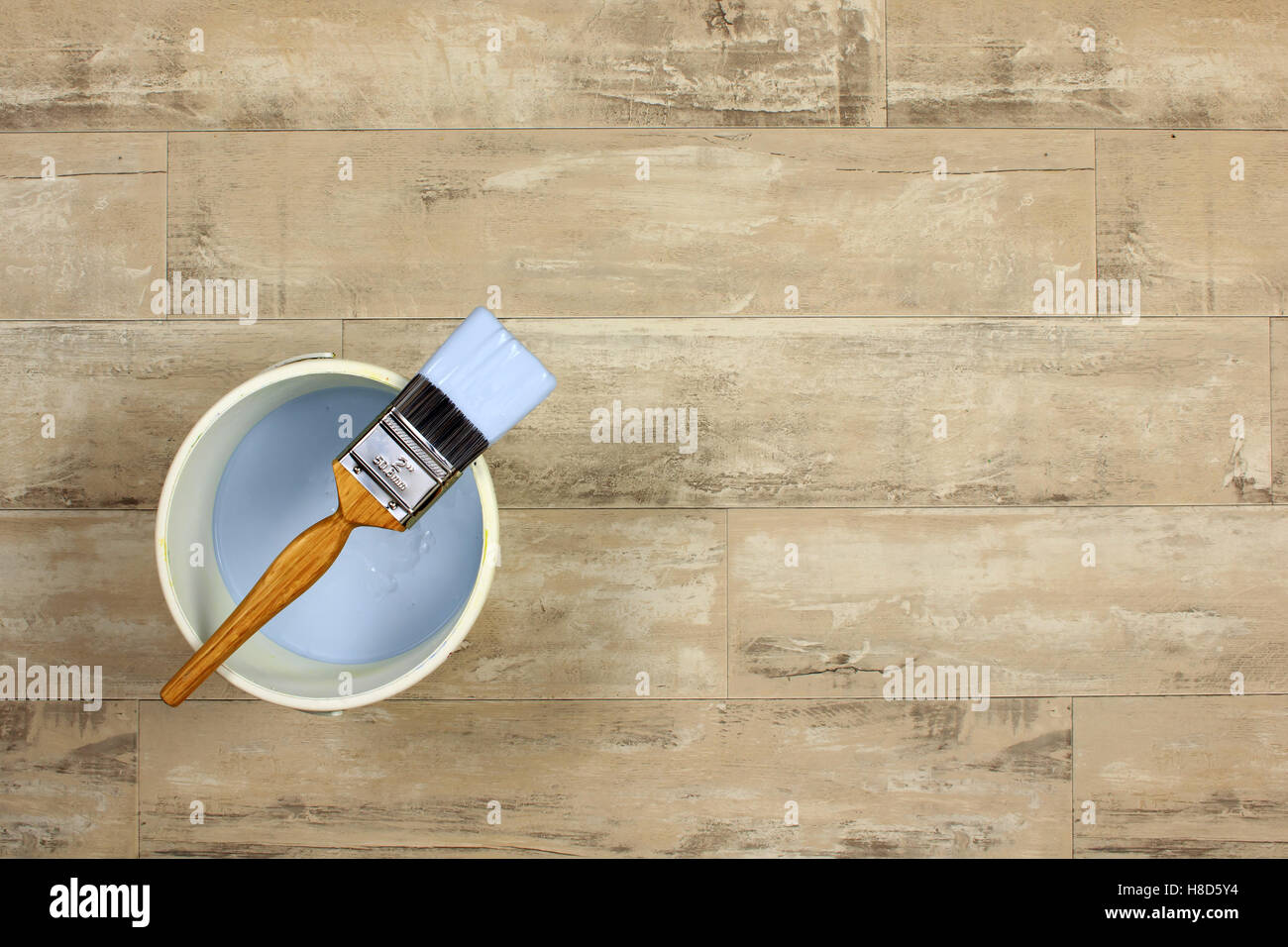 Caricate il pennello collocato attraverso una vernice bianca bollitore pieni di luce la vernice blu su uno squallido stile pavimento in legno Foto Stock