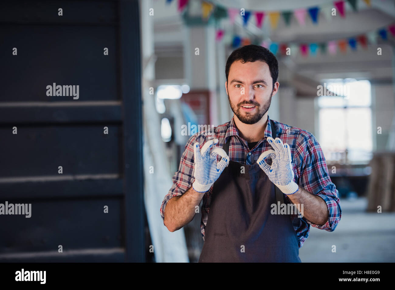 Lavoratore sorridente gesticolando doppio segno OK in officina Foto Stock