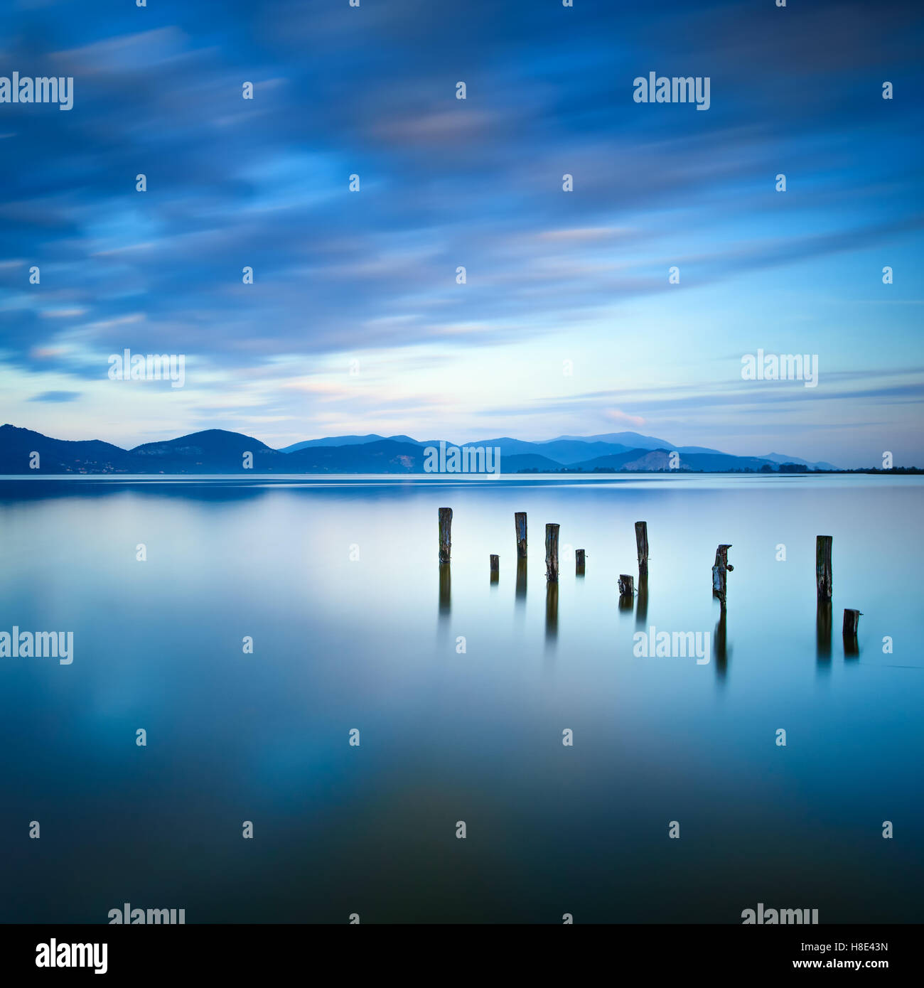Il molo di legno o molo rimane sul lago blu tramonto Cielo e acqua di riflessione. Una lunga esposizione, Versilia Massaciuccoli, Toscana, Italia Foto Stock