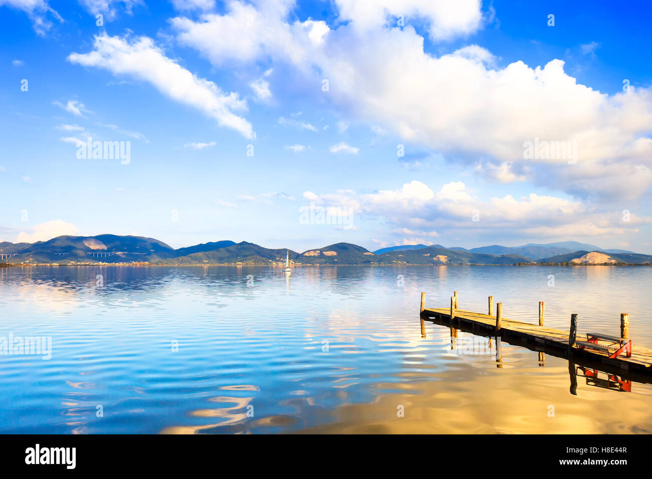 Il molo di legno o un pontile e su un lago blu tramonto e il cielo nuvoloso la riflessione sull'acqua. Versilia Lago di Massaciuccoli, Toscana, Italia. Foto Stock