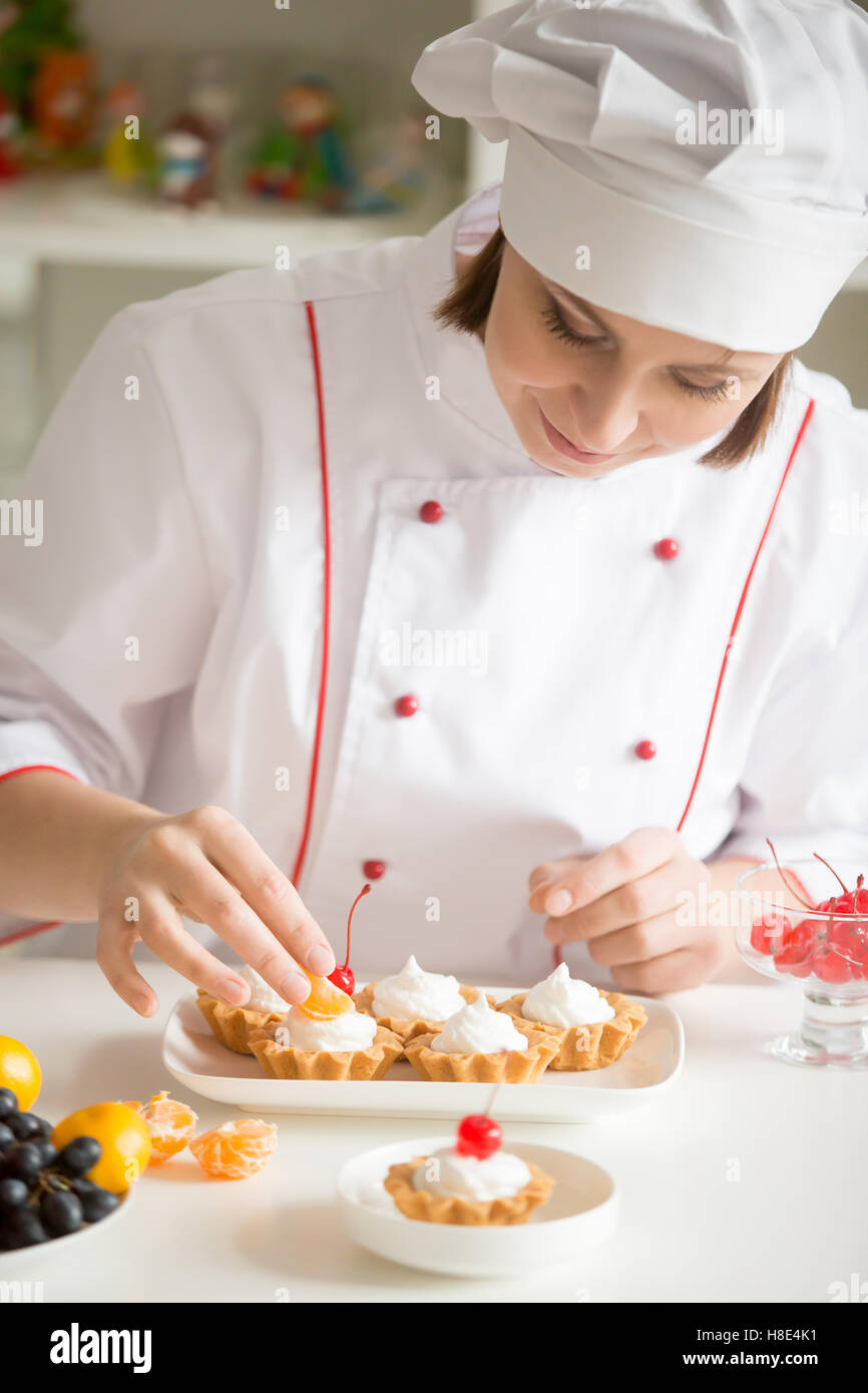 Femmina professionale pasticcere decorare mini crostate di frutta Foto Stock
