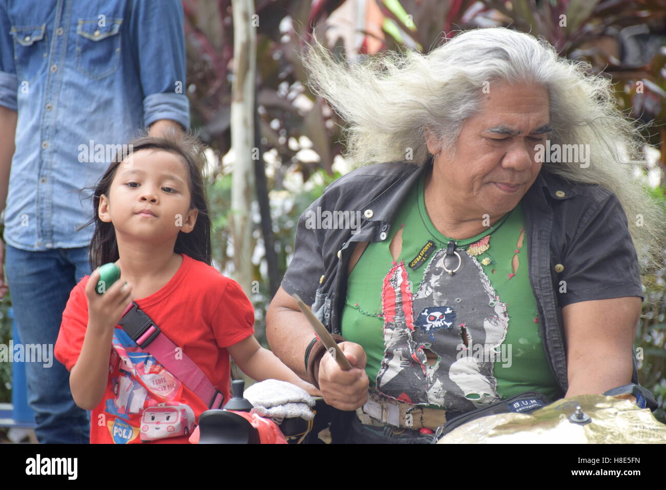 Malaysian uomo bianco con i peli lunghi la riproduzione di musica in strada con il suo nipote di Kuala Lumpur in Malesia Foto Stock