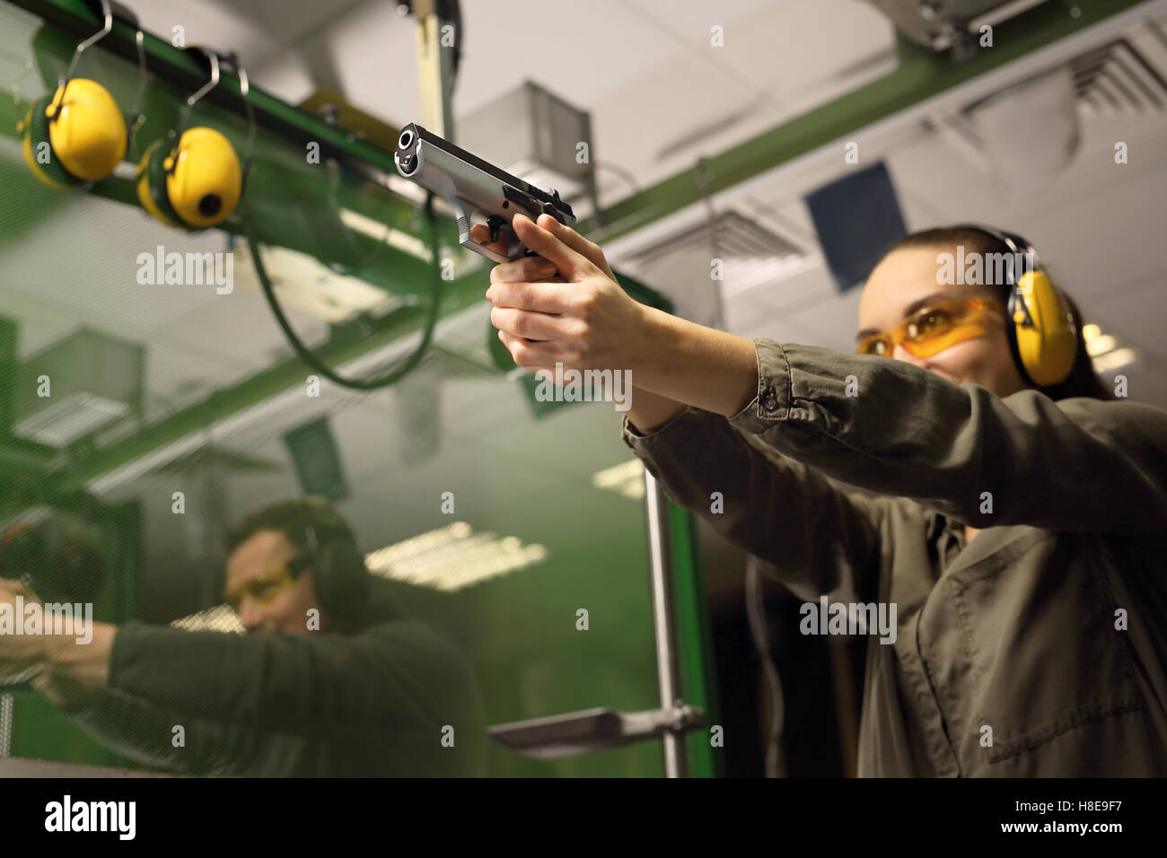 Donna spara una pistola a un poligono di tiro. Imparare a sparare una pistola. Foto Stock