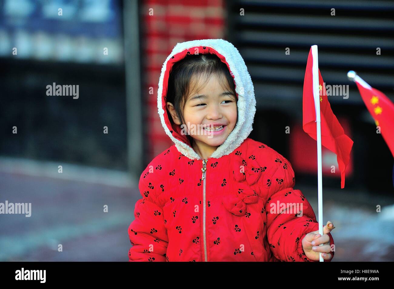 Bambina sventola una bandiera cinese come ella applauditi atleti impegnati nel 2016 Maratona di Chicago. Chicago, Illinois, Stati Uniti d'America. Foto Stock