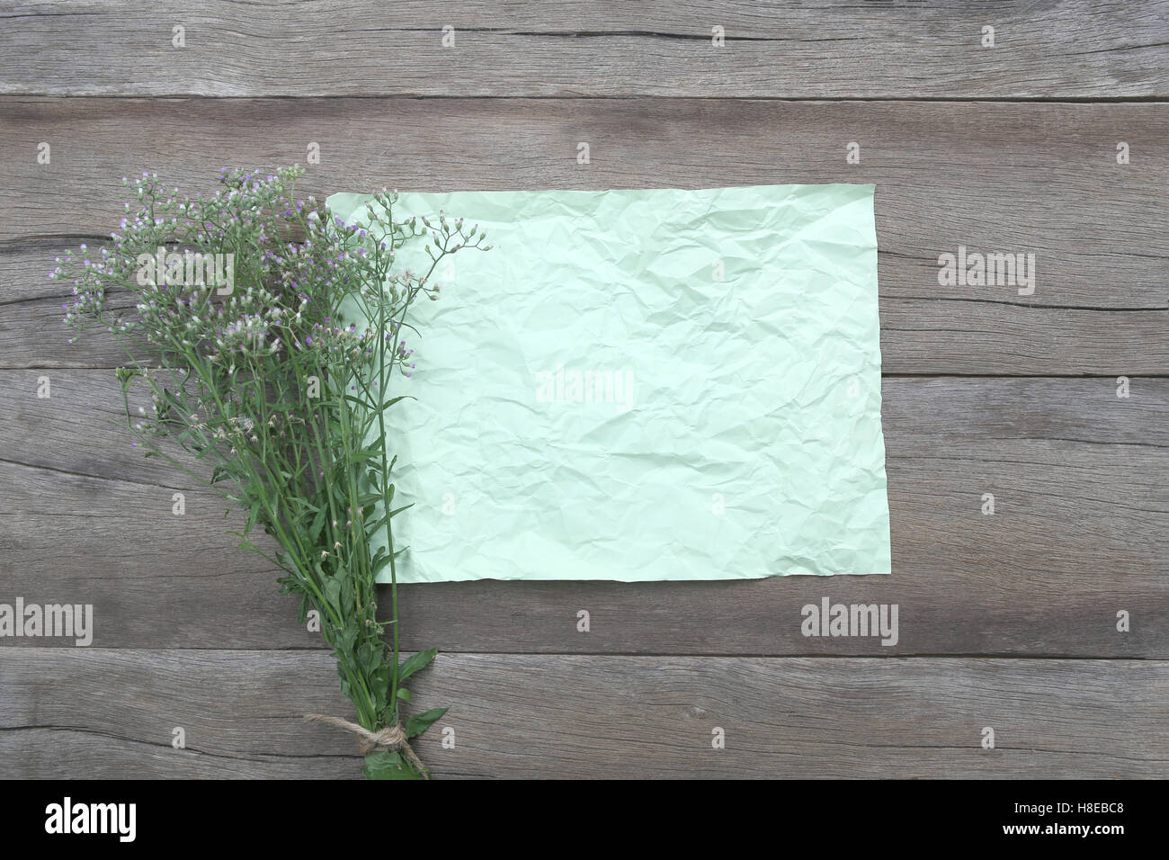 Bouquet di fiori e di erba stropicciata libro verde su un legno marrone dello sfondo. Foto Stock