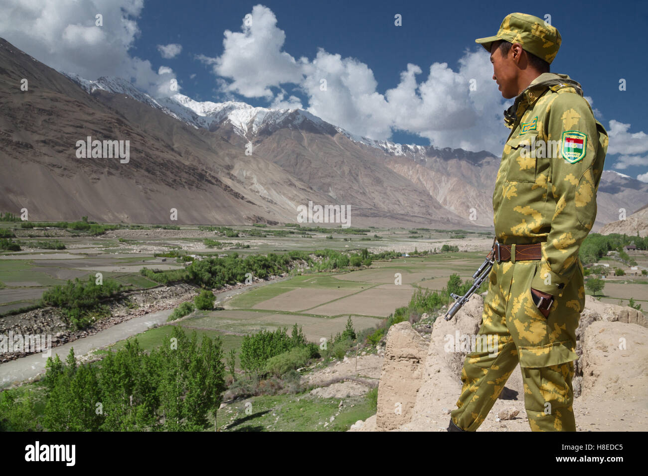 Un militare tagiko è guardare oltre il fiume Panj, nel Wakhan Valley, dal lato tagiko, Afghanistan è all'altro lato del fiume Foto Stock