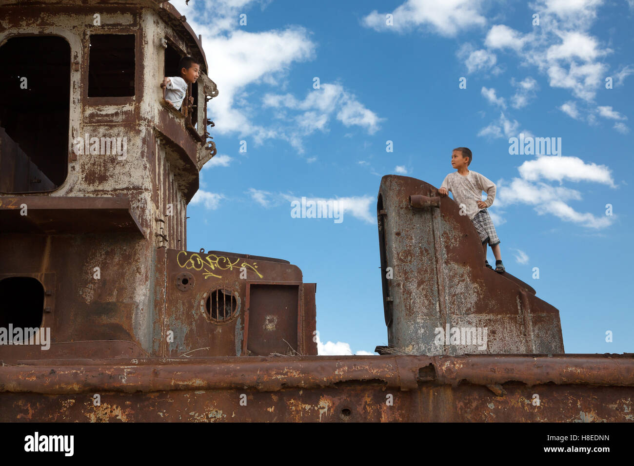 Bambini che giocano sulla barca abbandonata - Moynaq - Aral - Uzbekistan - Karakalpakstan - Asia Foto Stock