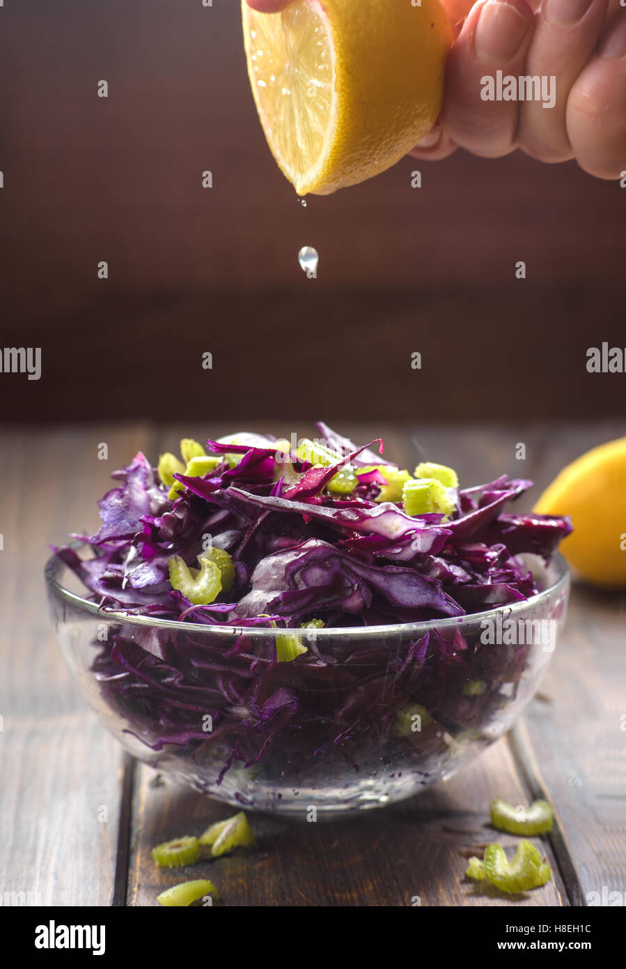 La caduta di mano di succo di limone su rosso insalata di cavolo Foto Stock