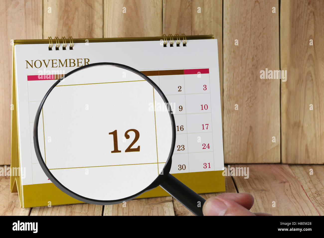 Lente di ingrandimento in mano sul calendario è possibile guardare dodicesimo giorno del mese,Focus numero dodici nel novembre,concetto in business e m Foto Stock