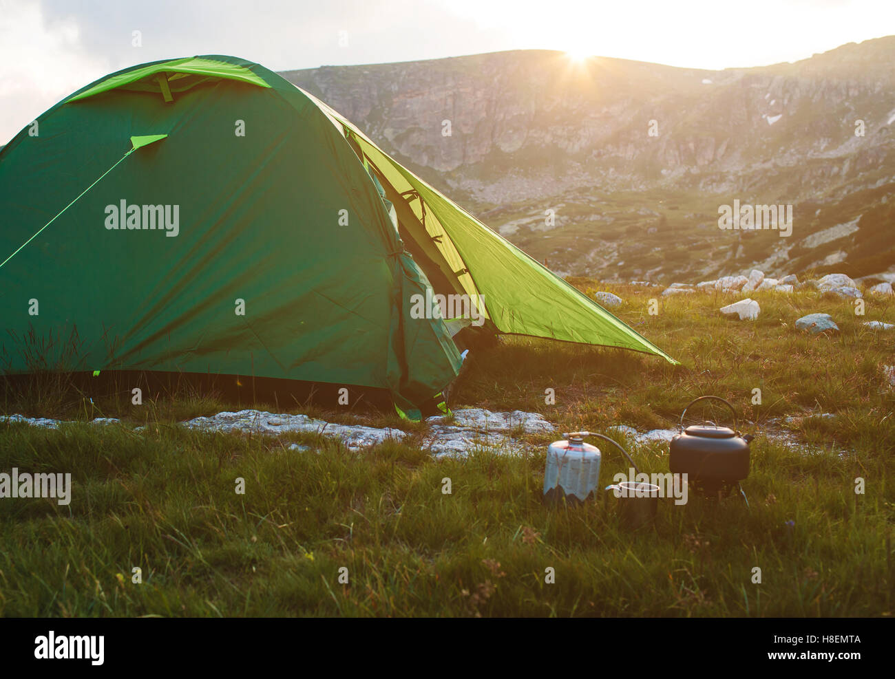 Camping teiera e il tappo sul prato all'orario di alba. Le montagne della Bulgaria. Foto Stock