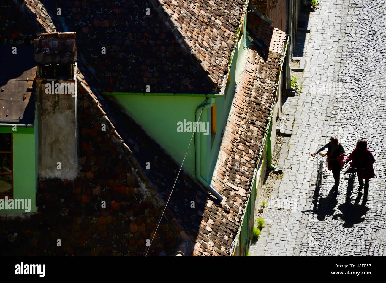 Persone che camminano con biciclette da città vecchia strada. Sighisoara, Romania Foto Stock