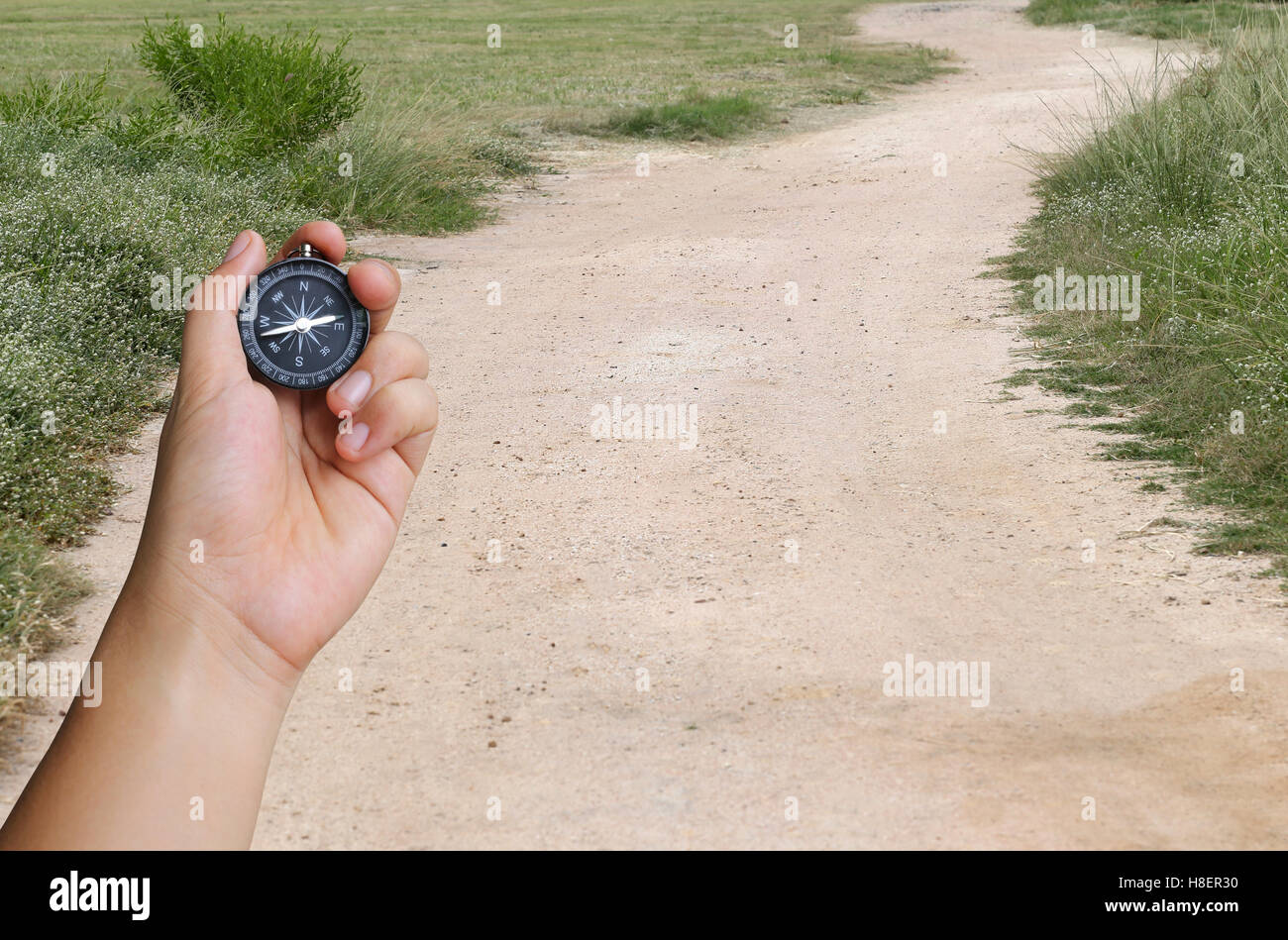 La mano di un uomo con una bussola e strada di campagna,concetto di viaggio o di viaggio. Foto Stock