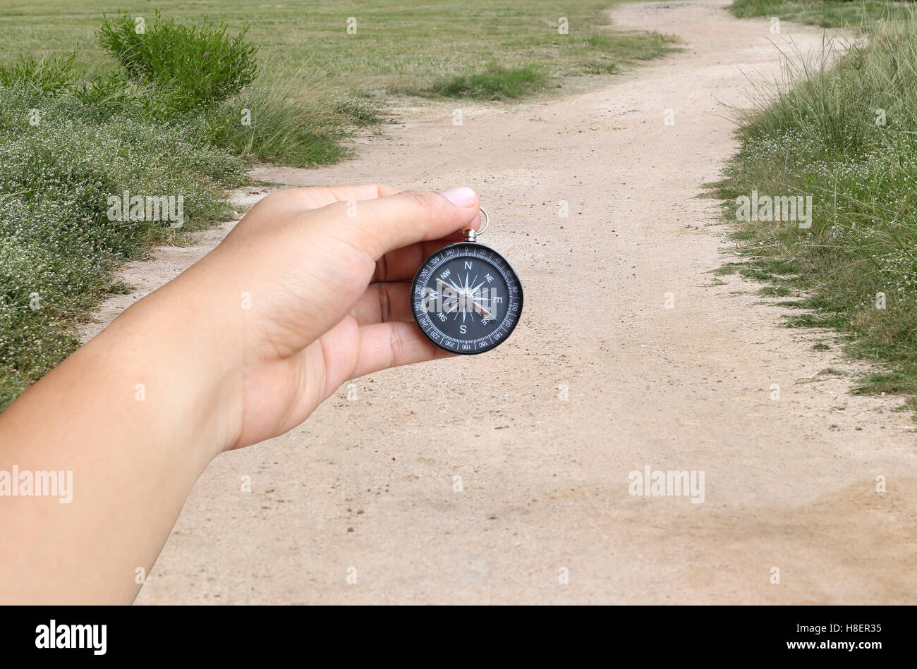 La mano di un uomo con una bussola e strada di campagna,concetto di viaggio o di viaggio. Foto Stock