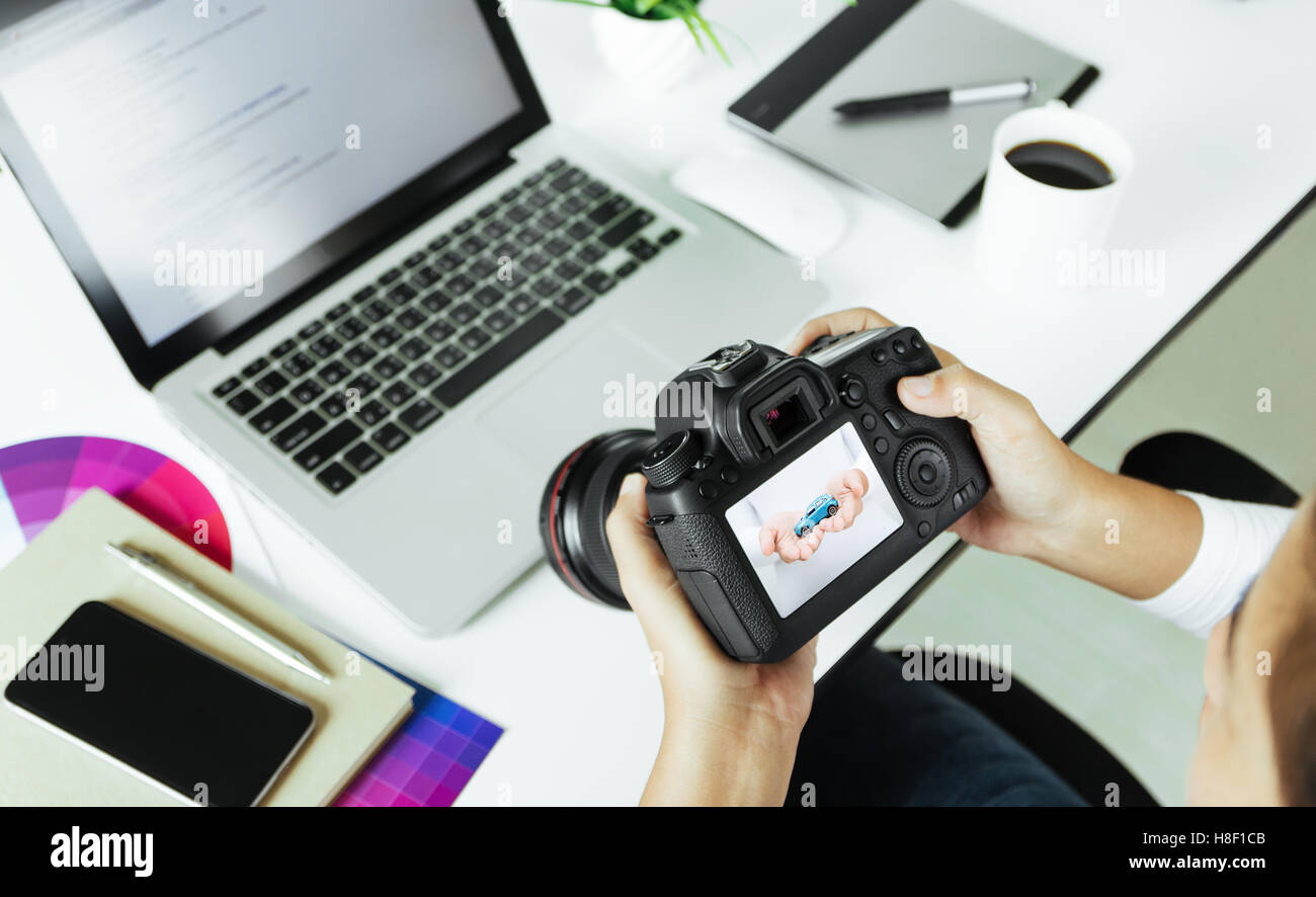 Fotografo controllo fotocamera reflex digitale sulla scrivania Foto Stock