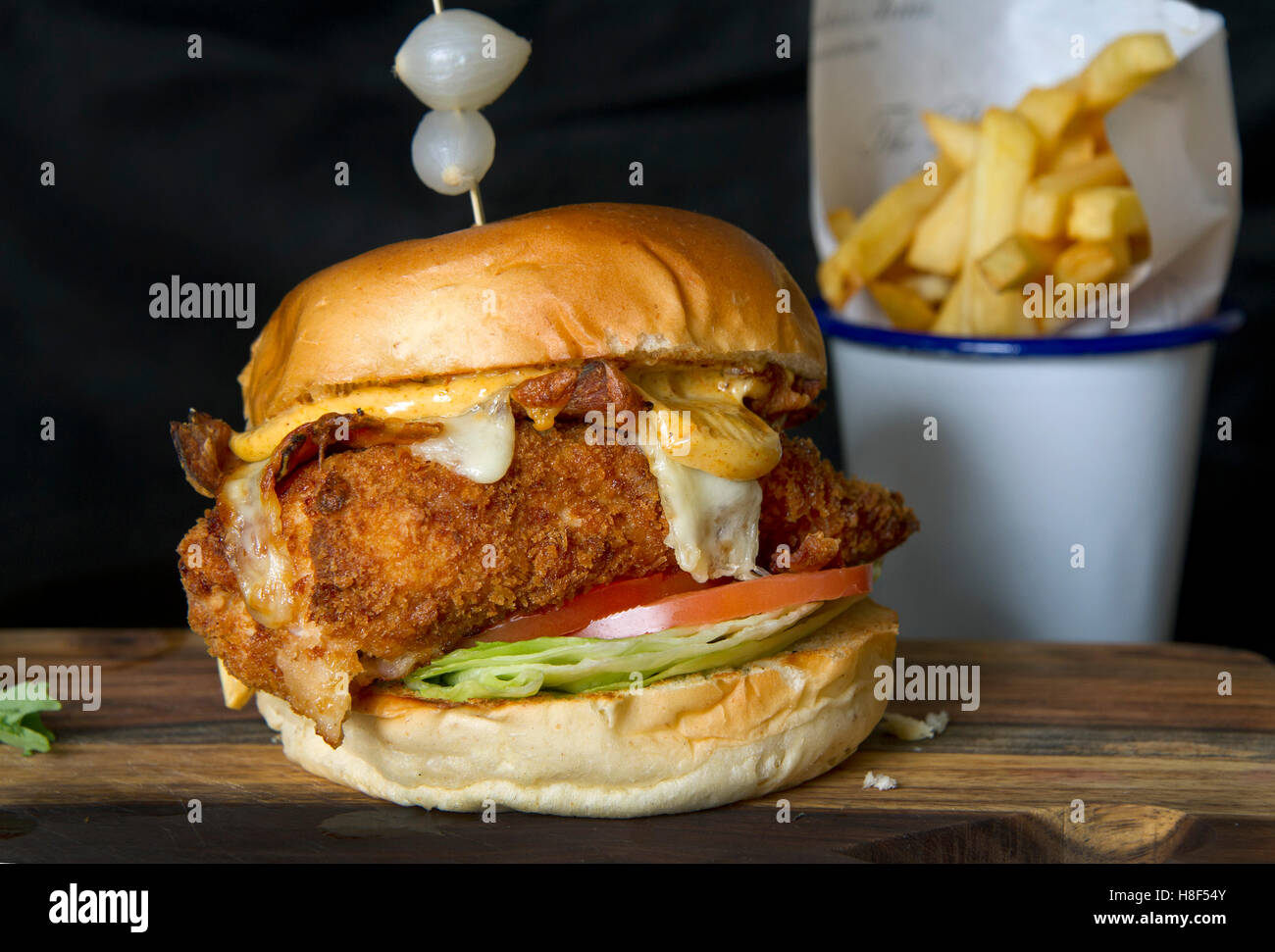 Beefburger e bun con chip (patatine fritte) servita su un tagliere di legno. un REGNO UNITO Foto Stock