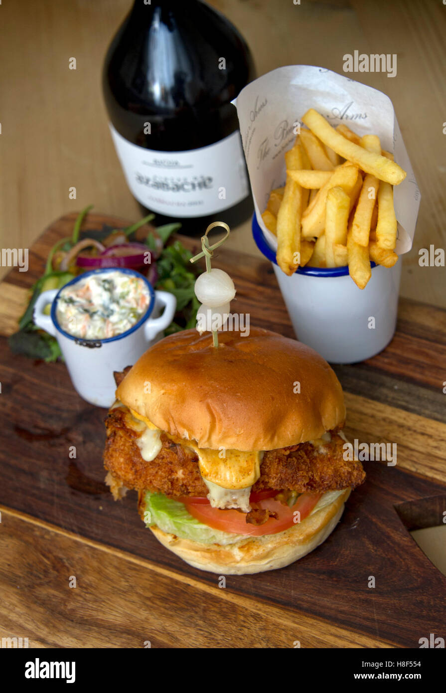 Beefburger e bun con chip (patatine fritte) servita su un tagliere di legno. un REGNO UNITO Foto Stock