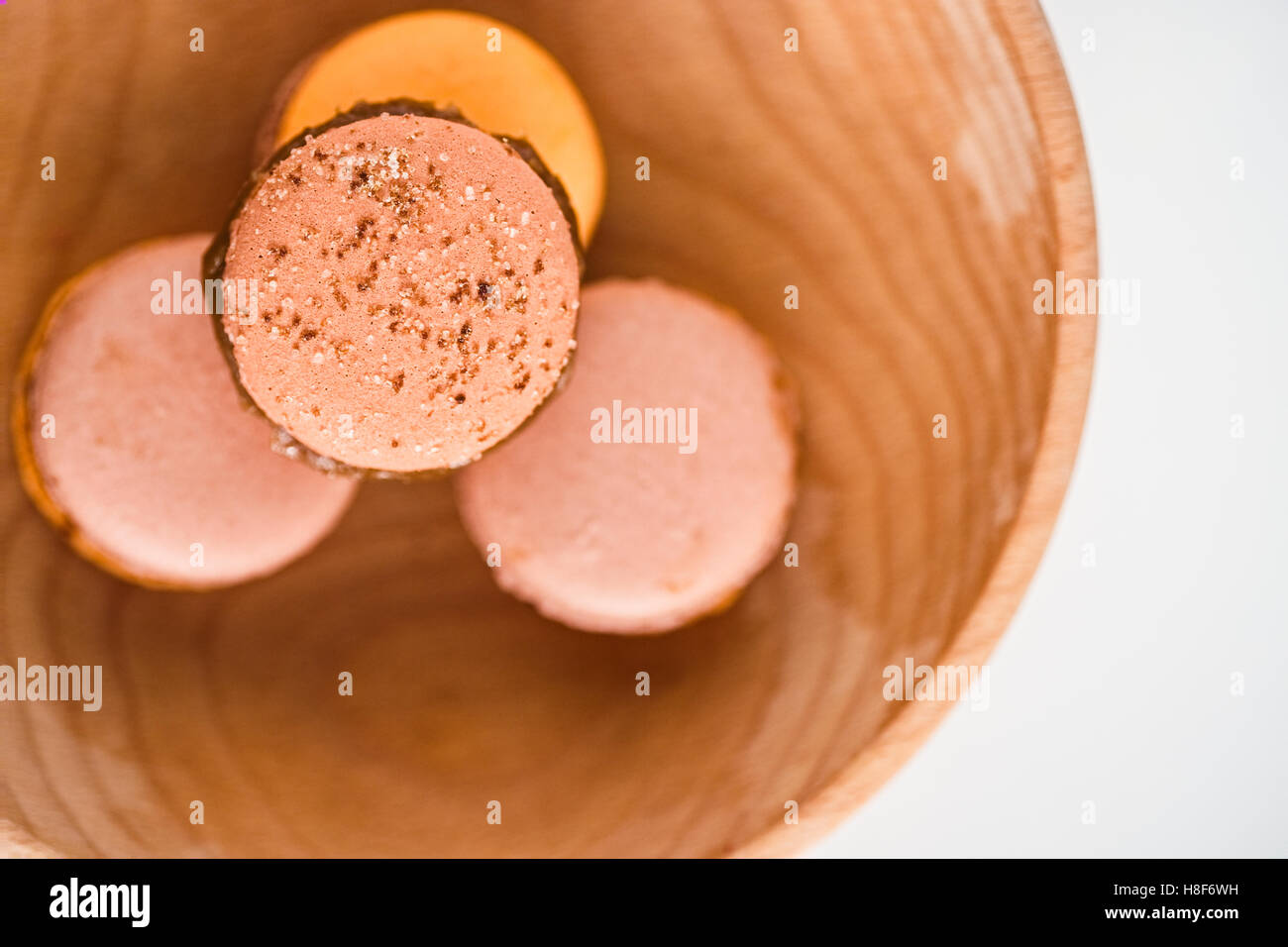 French macarons con glassa al cioccolato in rosa, arancione e caffè colori pastello. Sfondo bianco. Vista superiore Foto Stock