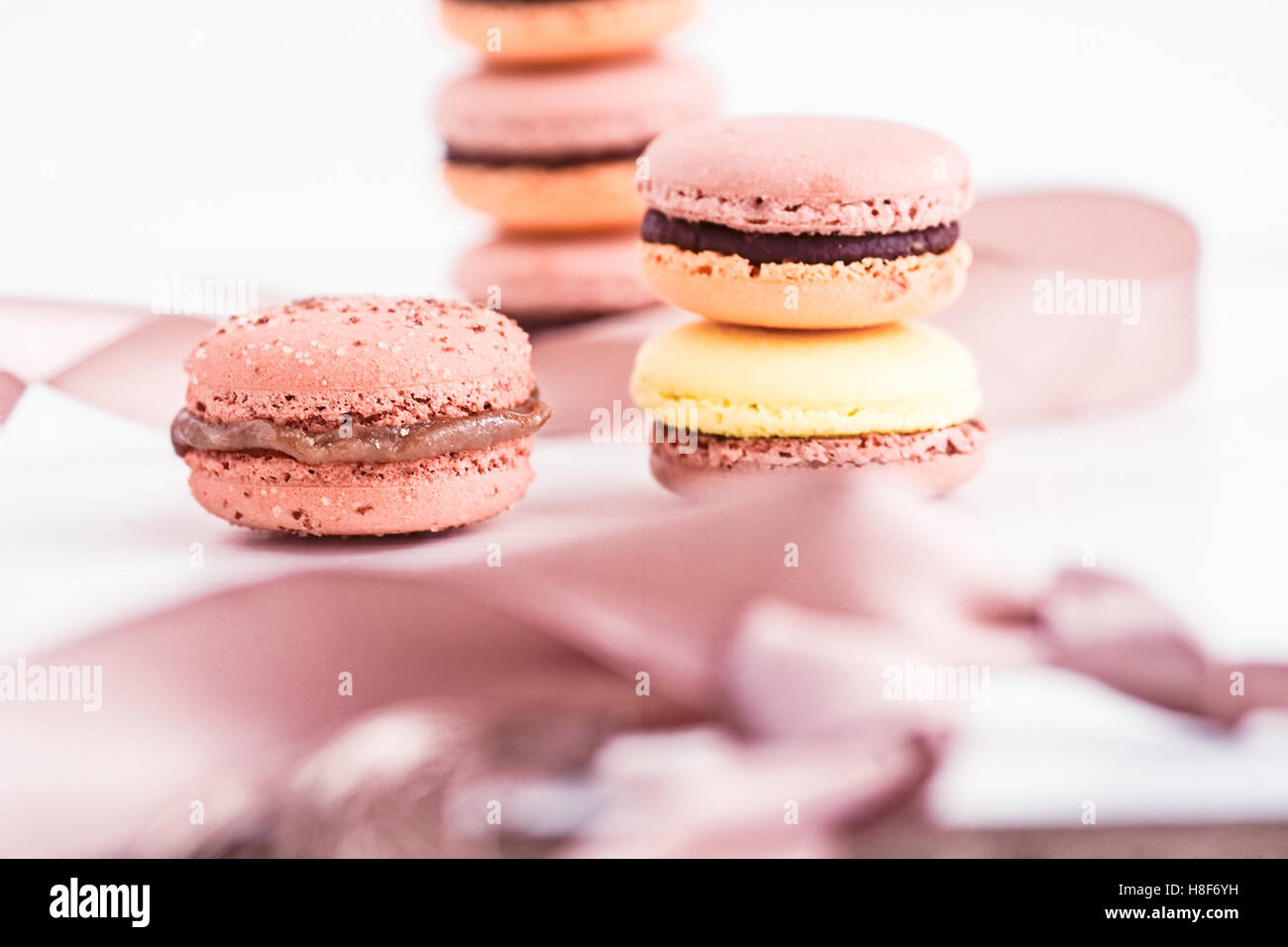 French macarons con glassa al cioccolato in colori pastello. Sfondo bianco Foto Stock