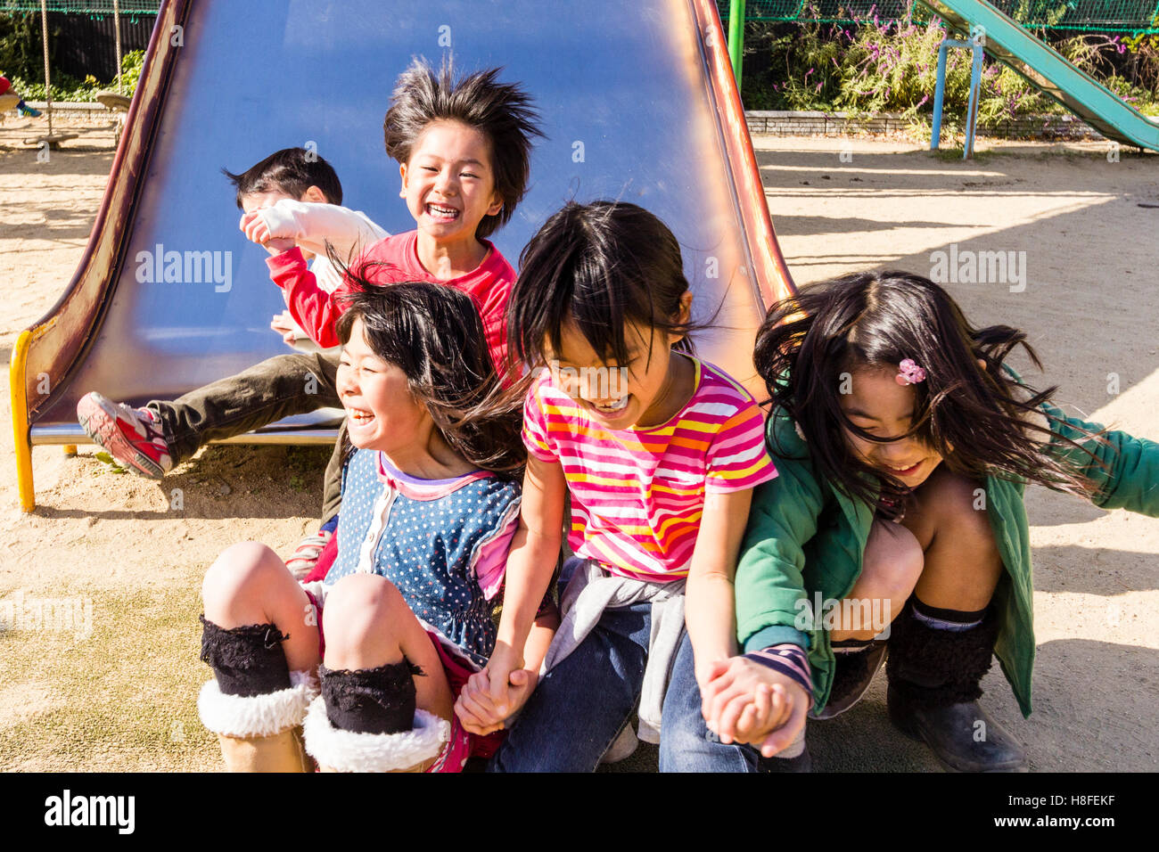 Il Giappone. Parco giochi scuola. Bambini, tre ragazze, 6-8 anni, salta  fuori da scorrere in fila, eccitati, gridando felicemente. Due ragazzi lo  scorrimento verso il basso dietro di loro Foto stock - Alamy