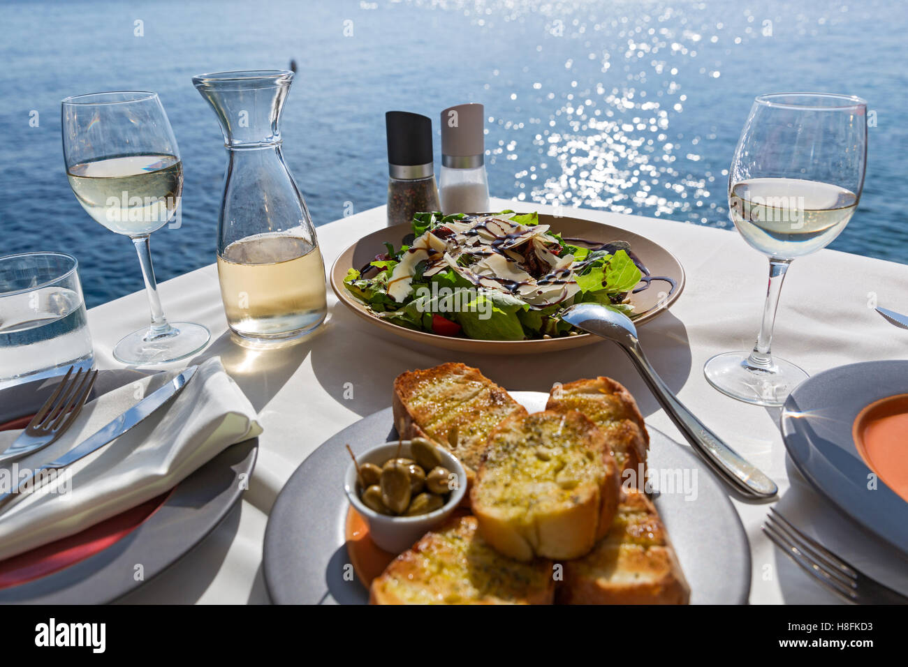 La tabella con il cibo e il vino sullo sfondo del mare Foto Stock