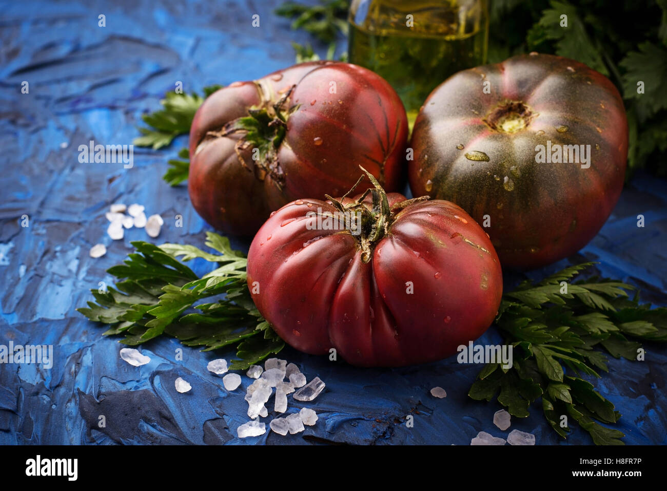 Pomodoro, il sale e il prezzemolo blu sullo sfondo di calcestruzzo. Messa a fuoco selettiva Foto Stock