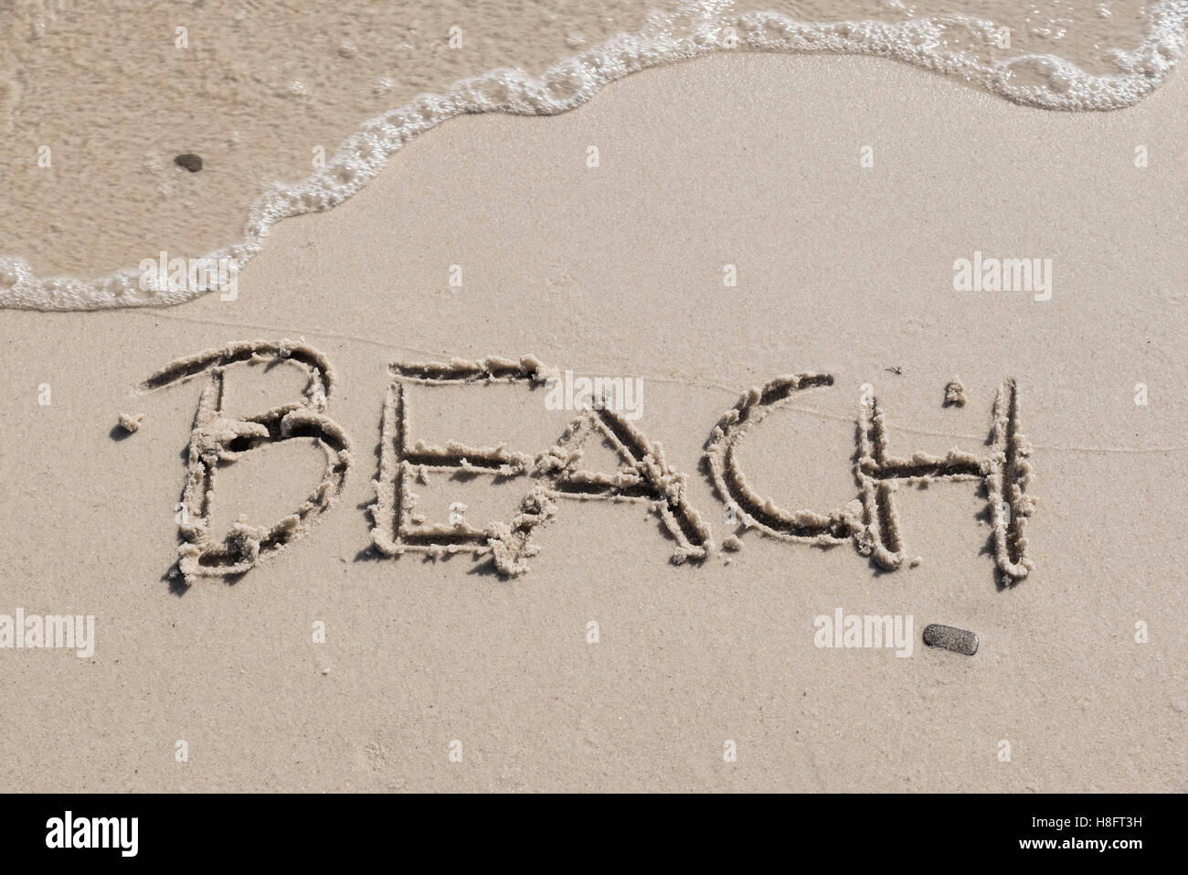 Spiaggia' scritto nella sabbia, fotografia orizzontale con piccola onda lavato fino sulla sabbia, Foto Stock