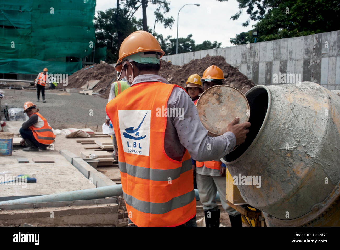 Lavoratori edili sono usando un mescolatore di cemento in un cantiere edile a Phnom Penh in Cambogia. Foto Stock