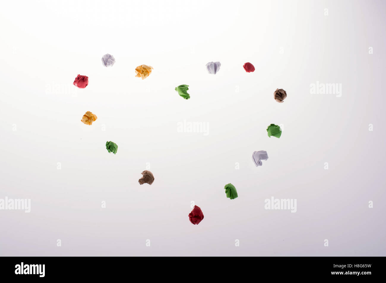 Colorata carta sgualcita forma a forma di cuore su uno sfondo bianco Foto Stock