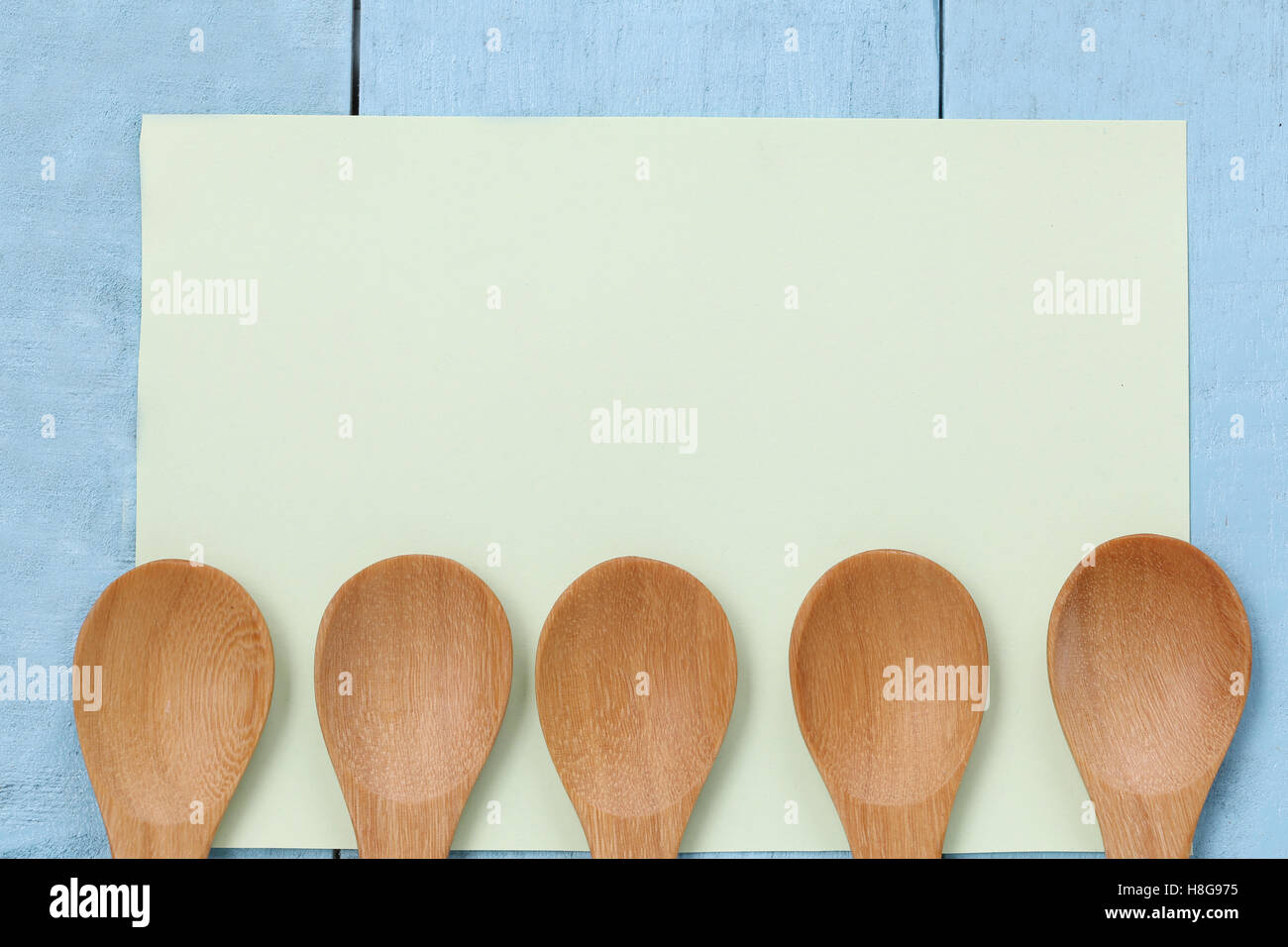 Il cucchiaio di legno sulla nota verde carta blu e tavolo in legno,concetto di stoviglie e utensili di cottura. Foto Stock