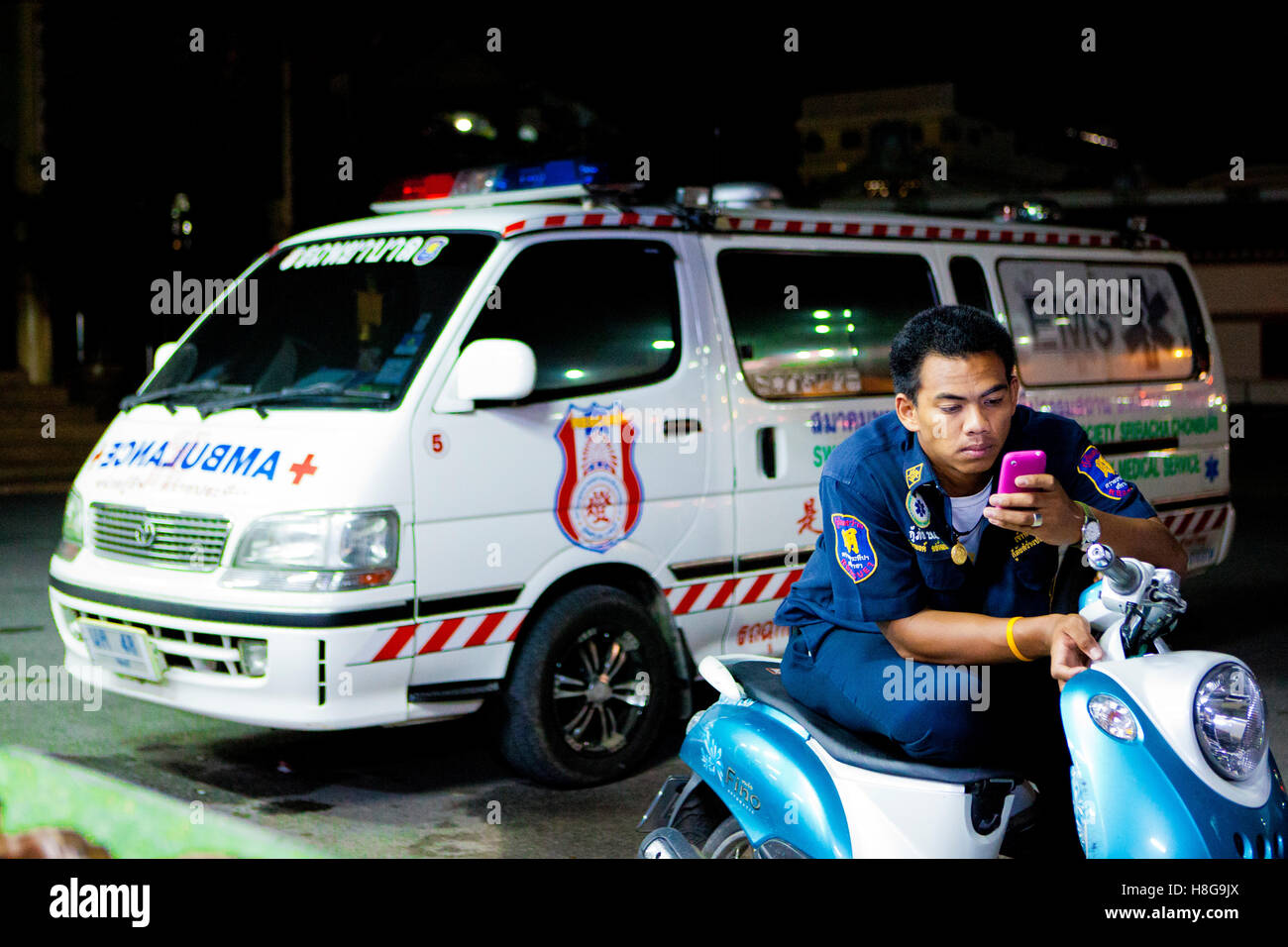 Un membro di Sawang Prateep il servizio di emergenza medica utilizza il suo telefono cellulare durante il suo turno di notte. Sawang Prateep è uno dei molti Foto Stock