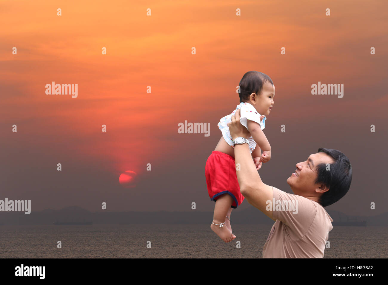 Padre sono state tenendo un bambino di fino e vista al tramonto sulla sera vicino al mare Thailandia,luce del crepuscolo bellissimo cielo,concept Foto Stock