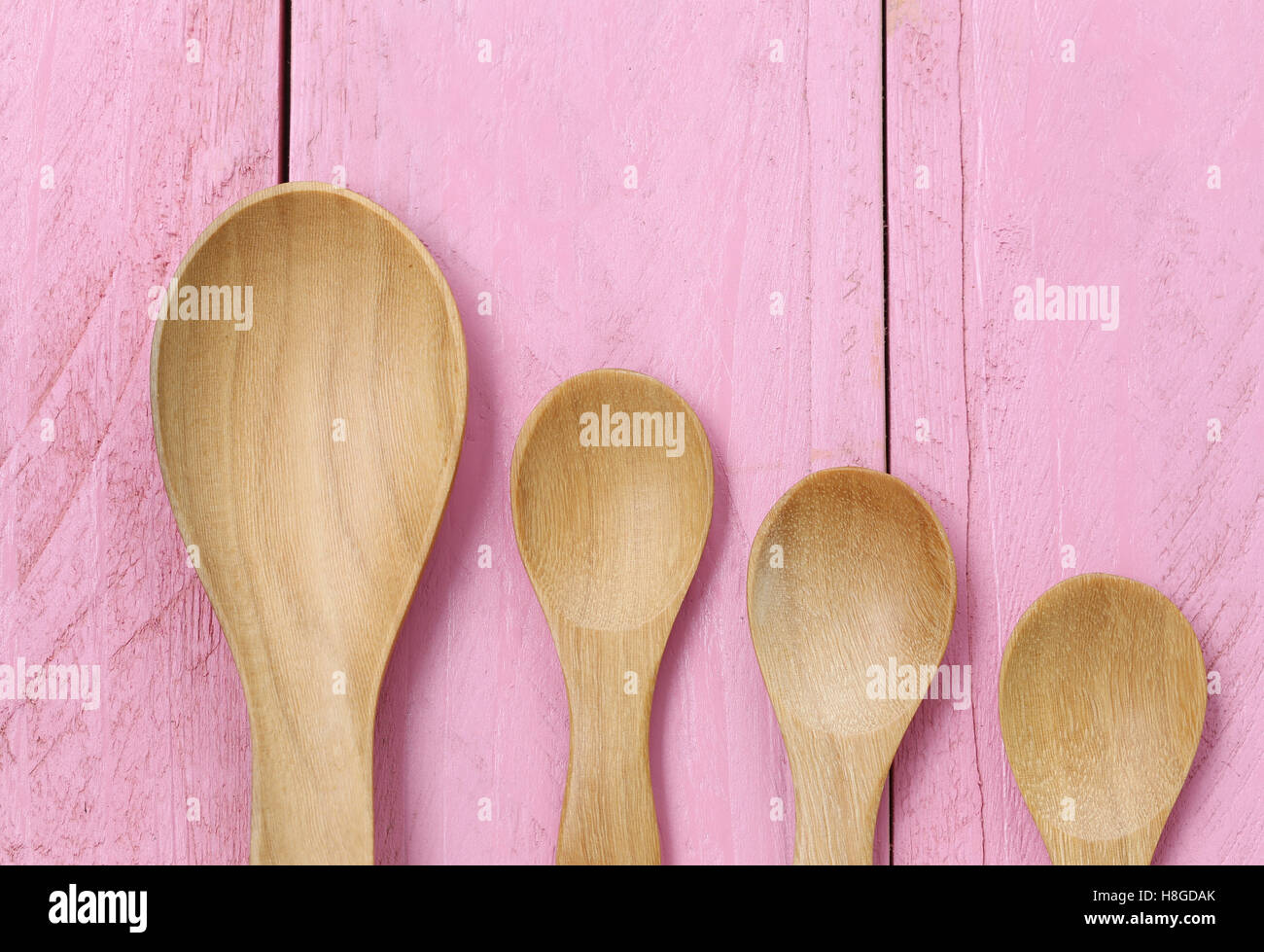 Il cucchiaio di legno sulla rosa dei pavimenti in legno,concetto di stoviglie e utensili di cottura. Foto Stock