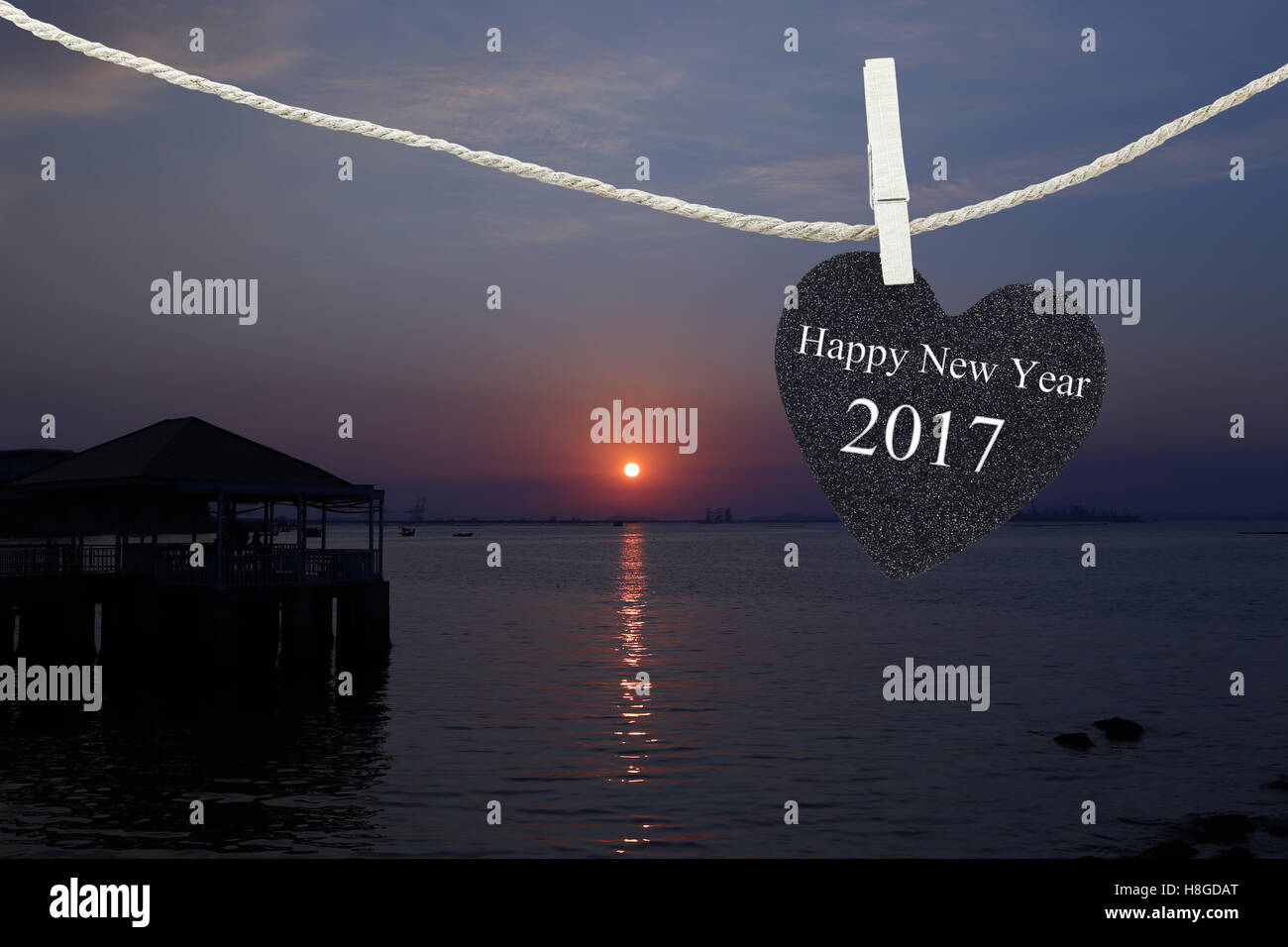 Cuore nero appeso sulla corda di canapa su sfondo di sunrise e sono felice anno nuovo 2017 testo. Foto Stock