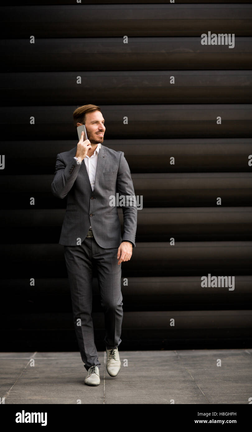 Imprenditore con un telefono dal muro nero Foto Stock