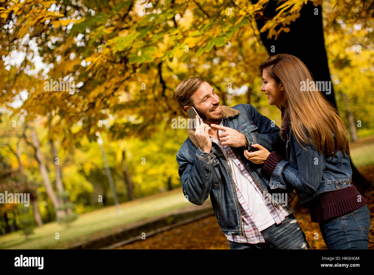 Amorevole coppia giovane in autunno park e uomo che parla al telefono Foto Stock