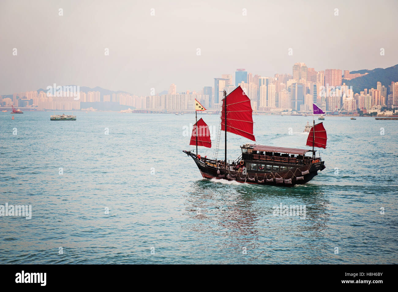 Tradizionale giunca Cinese barca con vele rosso a Hong Kong il Victoria Harbour al crepuscolo Foto Stock