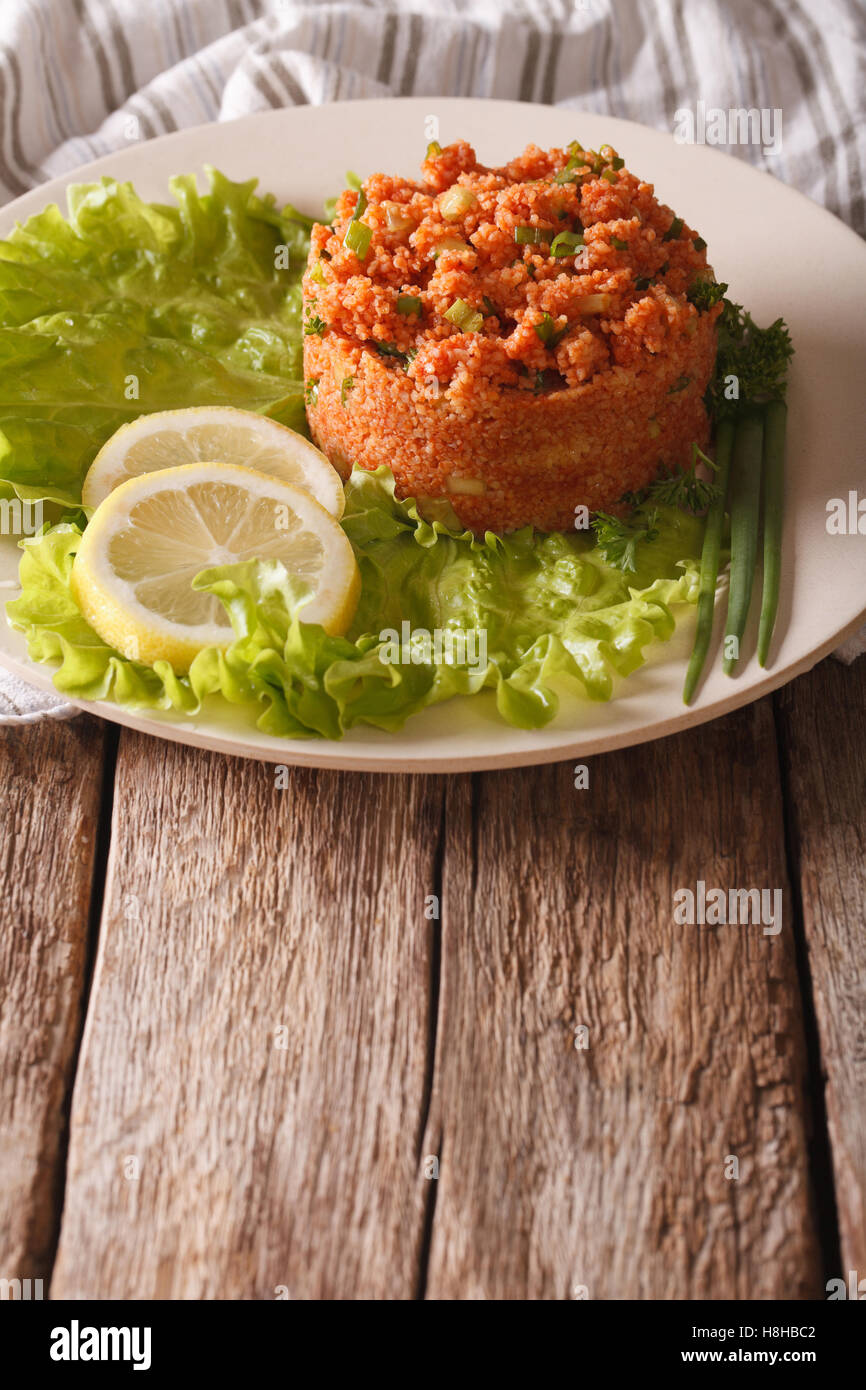 Bagno turco antipasto piccante k?s?r di bulgur con erbe di close-up su una piastra sul piano verticale. Foto Stock