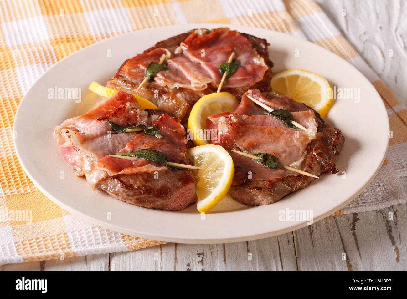 Saltimbocca di Vitello con salvia, prosciutto e fette di limone su una piastra di close-up orizzontale. Foto Stock