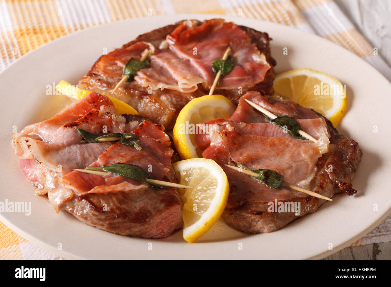 Carne bovina italiana Saltimbocca alla salvia, prosciutto e limone close-up su una piastra orizzontale. Foto Stock