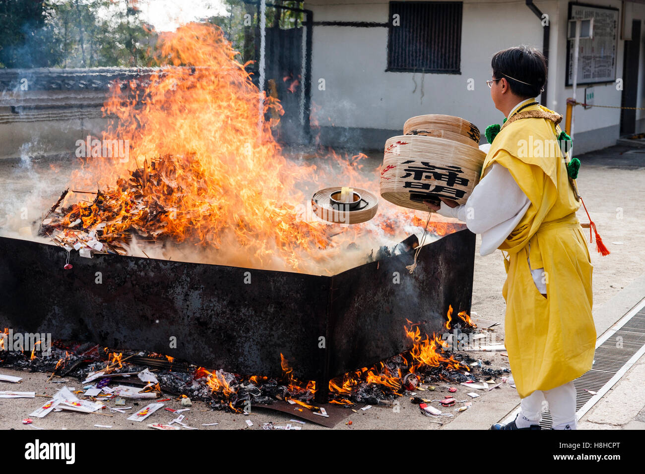 Giappone, Nishinomiya, Mondo Yakujin Tempio. Yamabushi sacerdote in vesti giallo gettando il Bambù Bocce nel fuoco durante la cerimonia di purificazione. Foto Stock