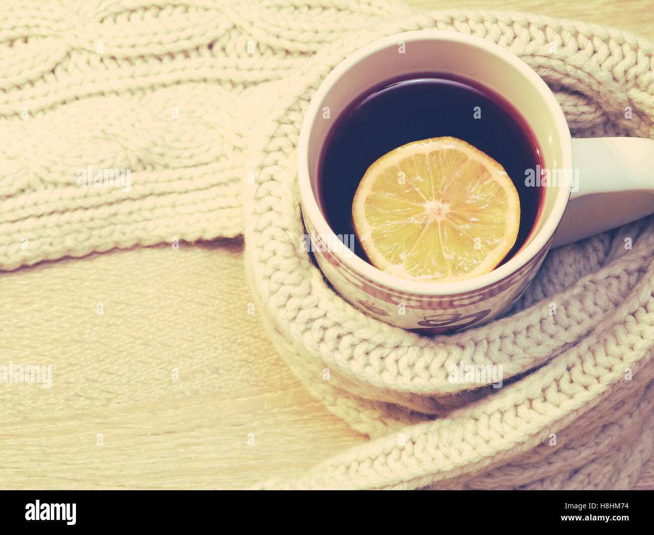 Tazza di tè caldo con limone vestito in un caldo inverno sciarpa Foto Stock