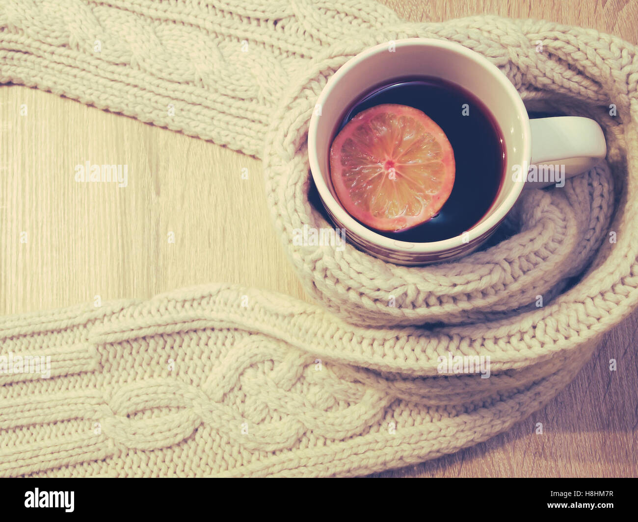 Tazza di tè caldo con limone vestito in un caldo inverno sciarpa Foto Stock